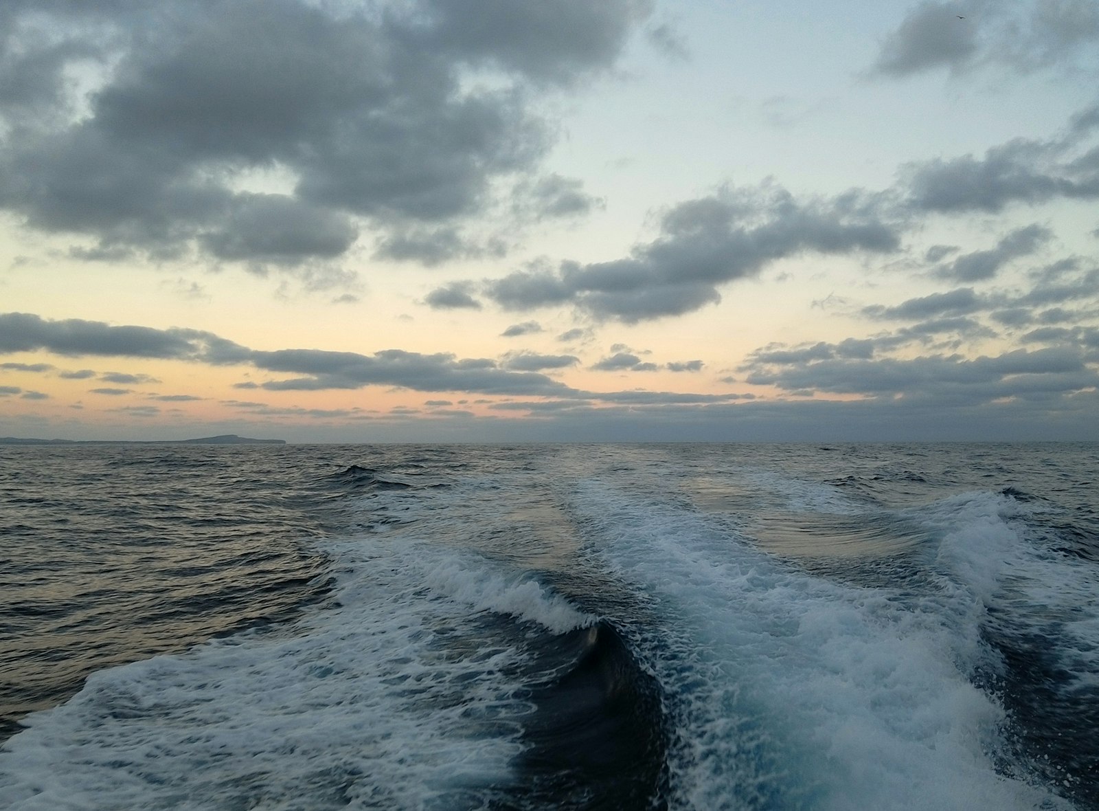 The wake of a yacht crossing open Mediterranean sea at sunset